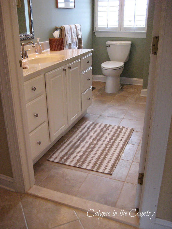 Bathroom with tan tile floors and white cabinets - tips for tiling a floor