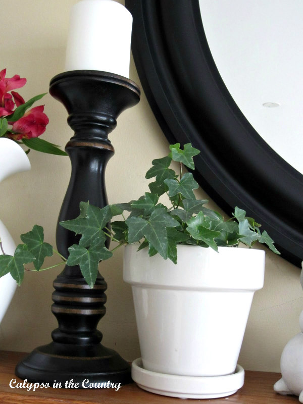 black candlestick and ivy in white flowerpot