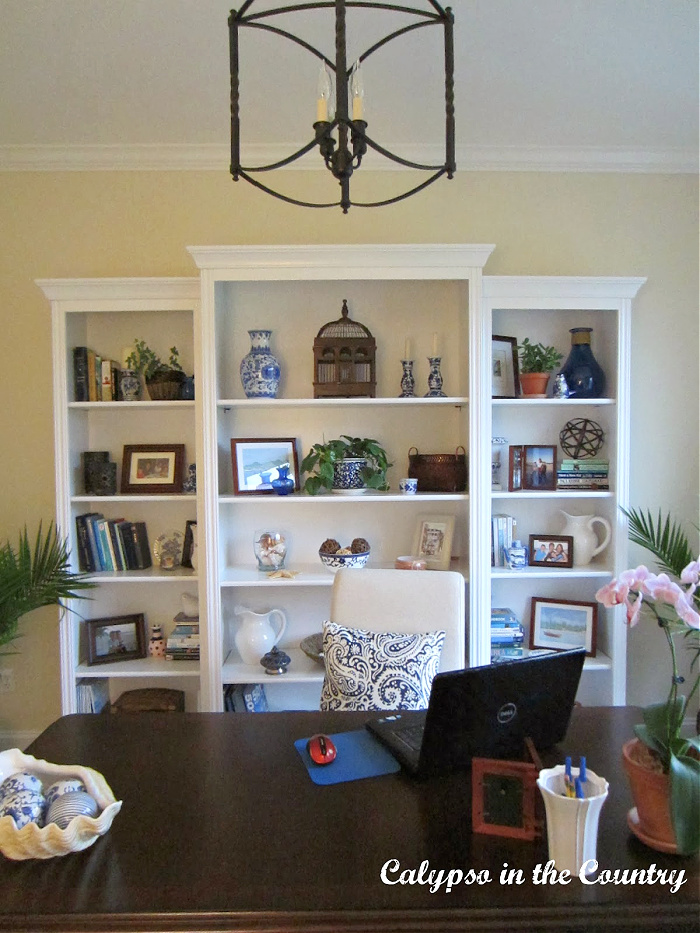 Blue and white home office with white bookcases and ceiling lantern