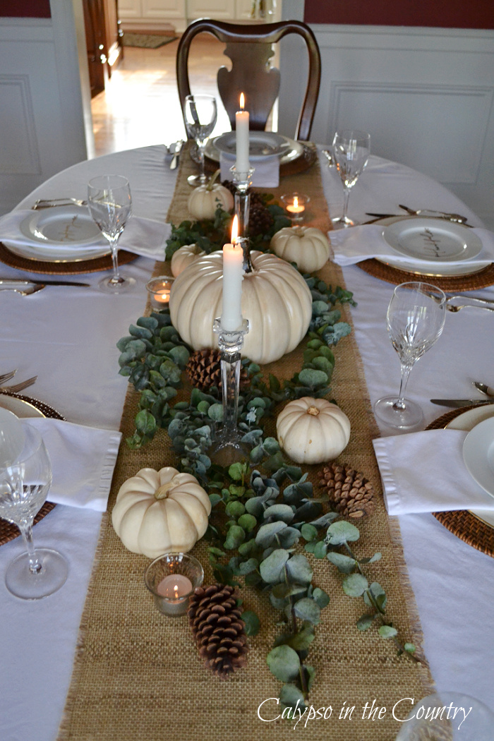 White pumpkins, candles and eucalyptus on burlap table runner - decorating with white pumpkins