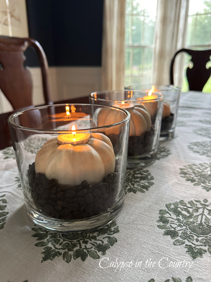 White pumpkin candles and coffee beans in glass hurricanes on table - decorating with white pumpkins