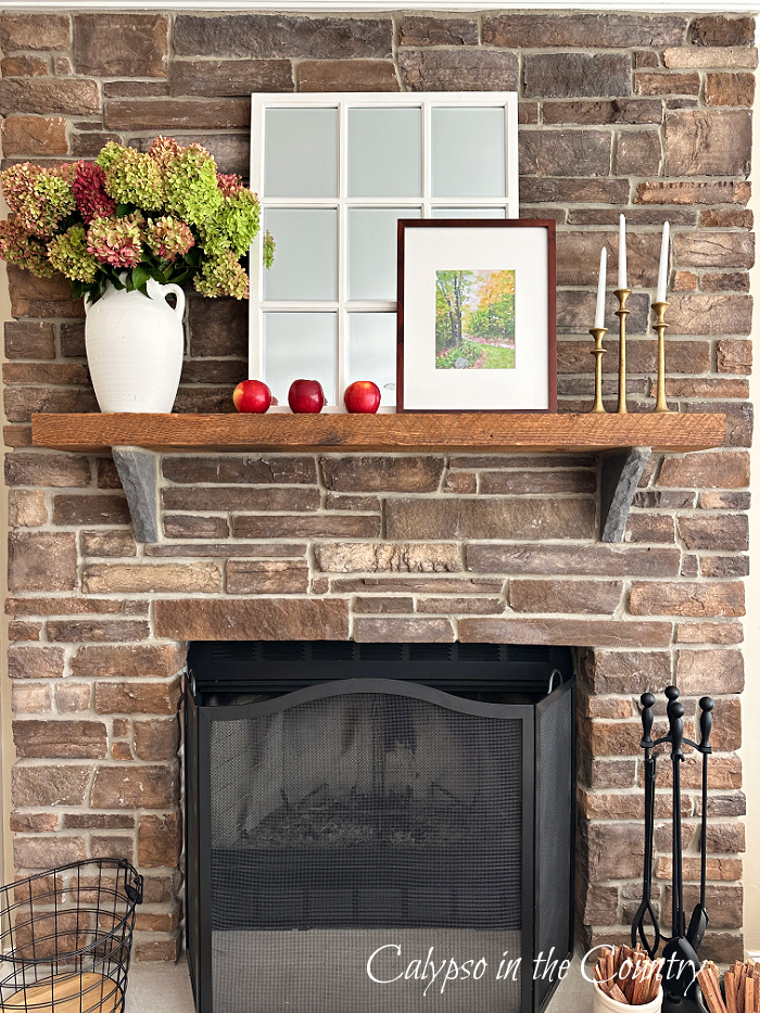 Stone fireplace styled for fall with hydrangeas, mirror and red apples - decorating with apples