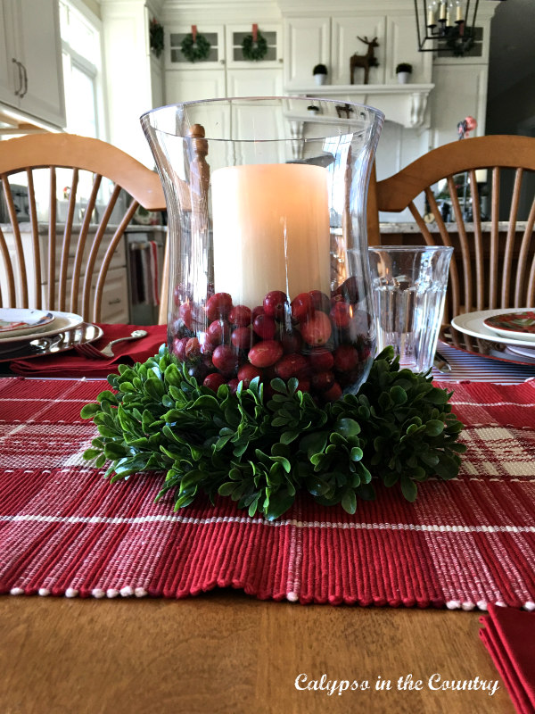 Glass hurricane filled with cranberries for a colorful and festive Christmas table