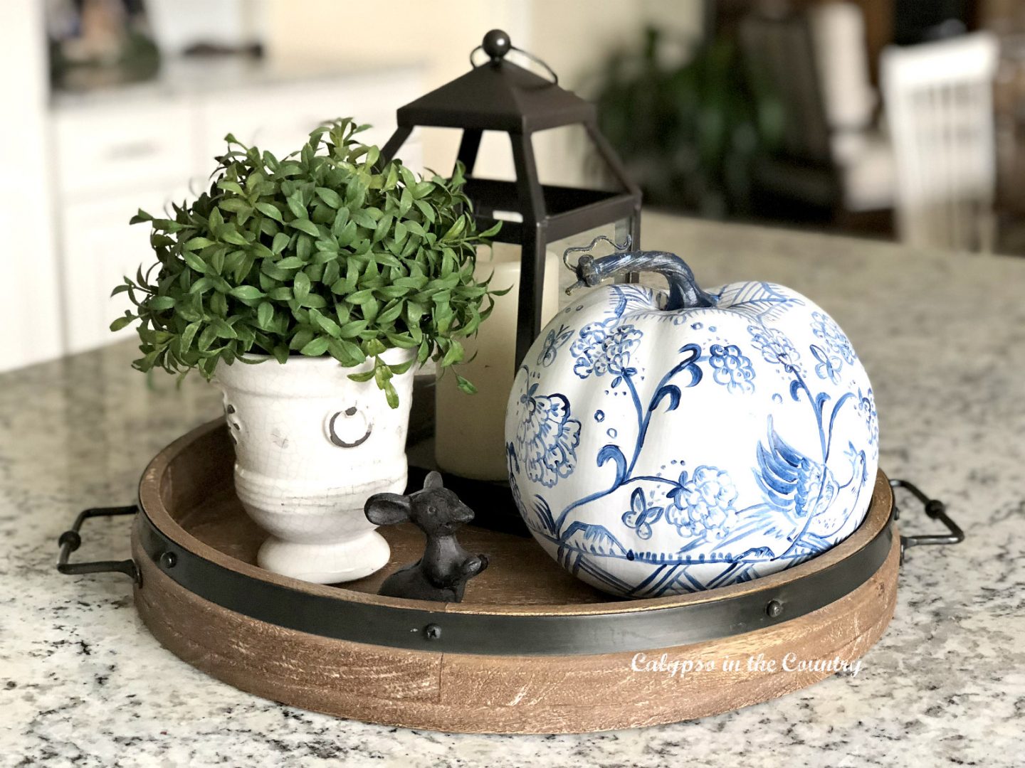 Blue and white painted pumpkin on rustic wood tray