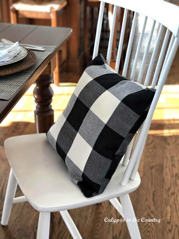 Black and white buffalo check pillow on white chair
