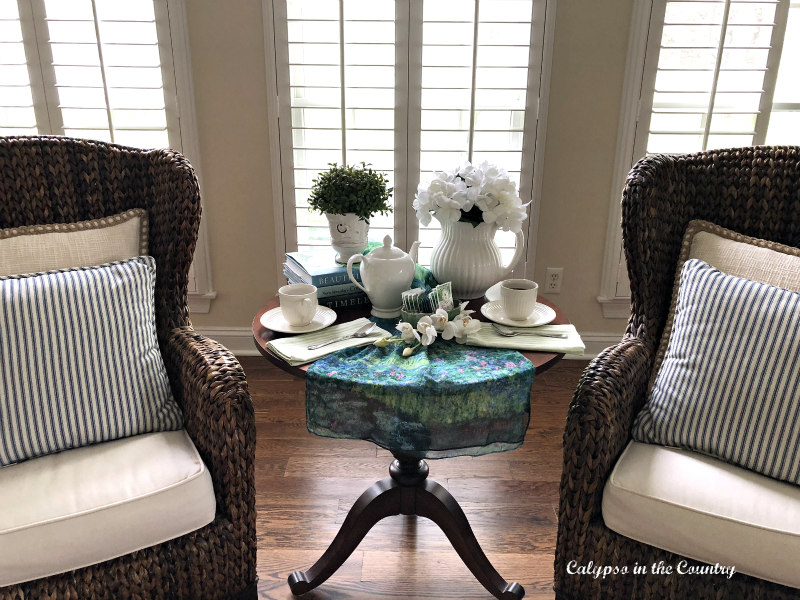 spring tea table between two seagrass chairs in front of windows - spring afternoon tea decor