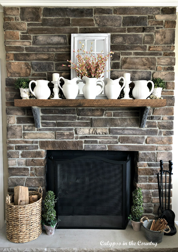 stone fireplace with white pitchers on mantel