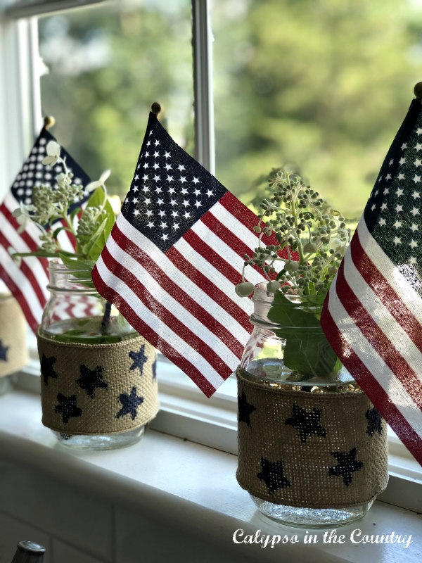 Mason jars and flags on windowsill - how to decorate for the 4th of july on a budget - #4thofjulydecor #americanflags #decoratingwithflags