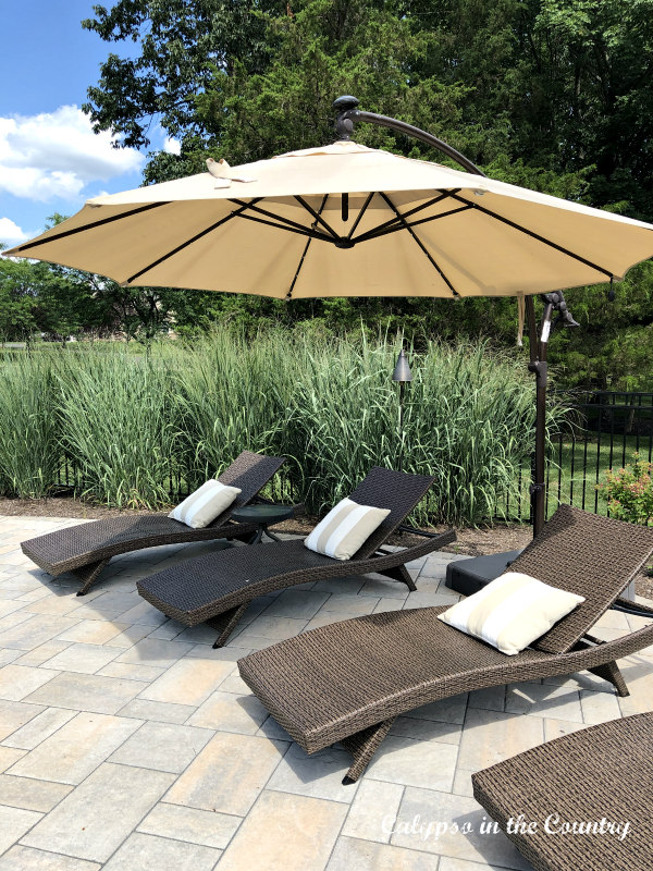 Outdoor wicker chaise lounge chairs with cantilever umbrella - backyard staycation ideas