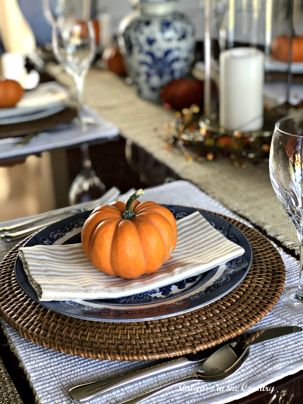 Blue and white place setting with mini orange pumpkin - ideas for fall table decor.
