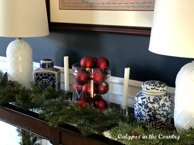 Red Christmas ornaments in glass container on table with blue and white porcelain