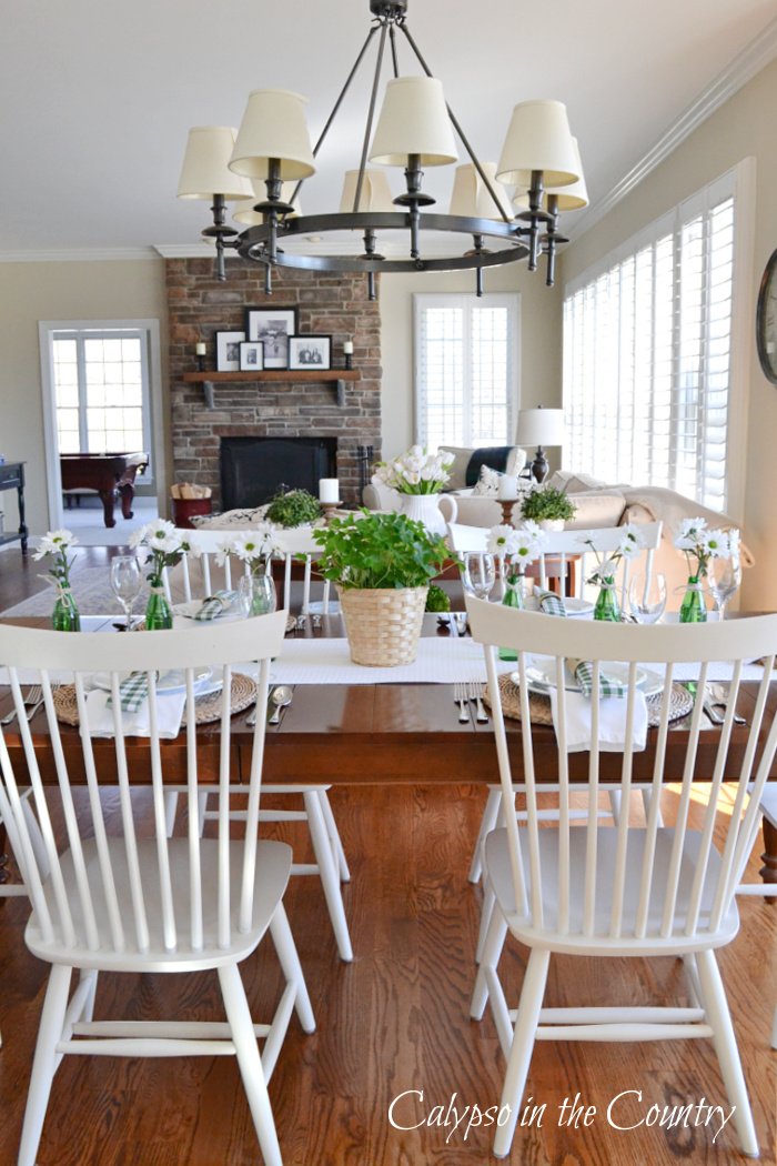 Green and white decorations on kitchen table with white chairs. - St Patricks Day table setting ideas