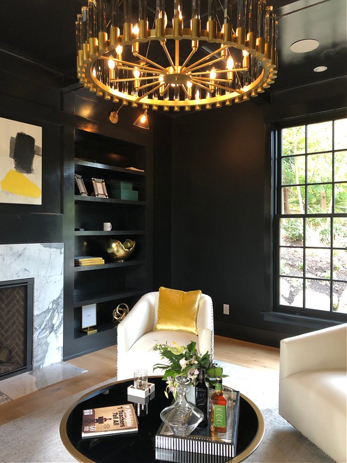 Den with black walls and gold chandelier - house design ideas