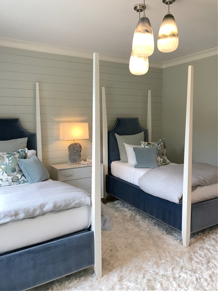 Twin four poster beds and gray shiplap wall