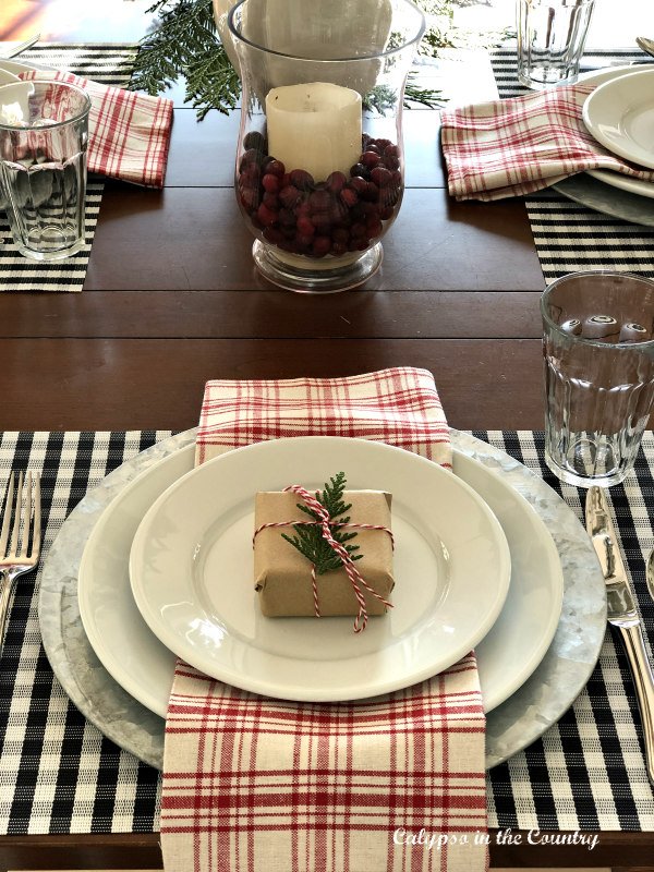 red and black tablesetting with cranberries in a glass hurricane - easy vase filler ideas for Christmas