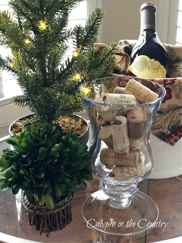 wine corks in glass vase next to greenery - simple decorating ideas