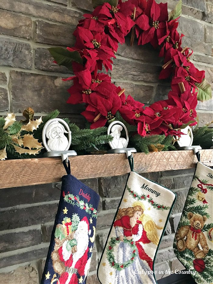 Red poinsettia wreath on stone fireplace - Christmas decorating with poinsettias