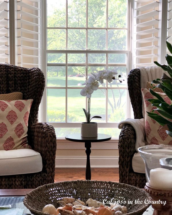 Open plantation shutters and two seagrass chairs - timeless and trasditional home decor