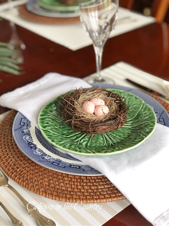 Easter eggs in nest on blue and green table setting