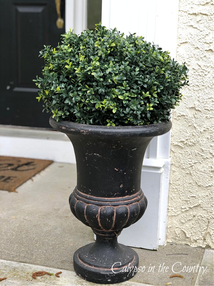 artificial boxwood plant in black urn planter - ways to decorate with fake plants