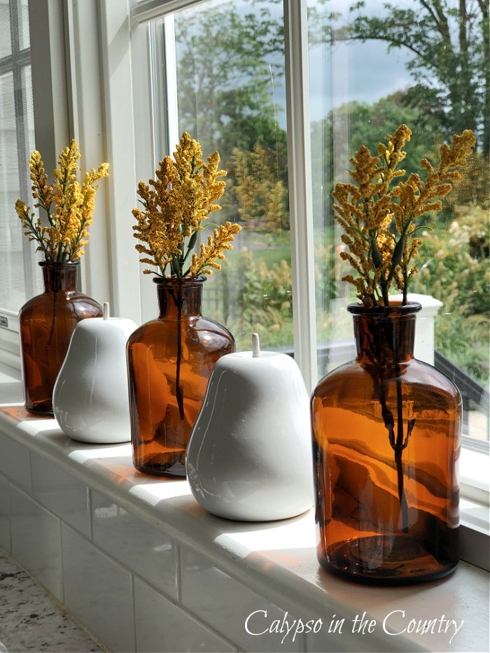 amber bottles in windowsill - neutral fall decor ideas