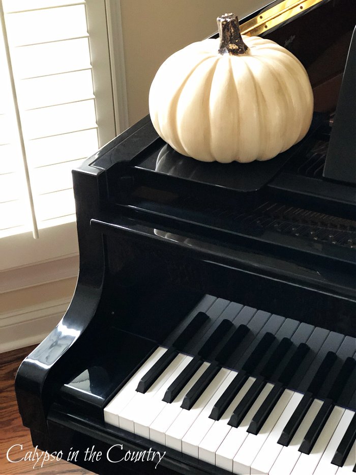 black piano decorated for fall with white pumpkin
