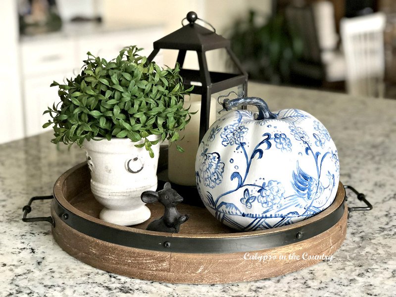 blue and white pumpkin and plant on round wood tray - kitchen island fall decor