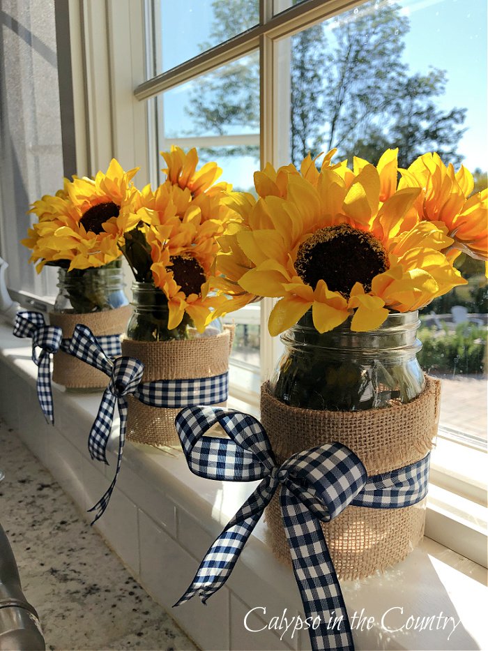 Sunflowers in burlap covered mason jars on kitchen window sill