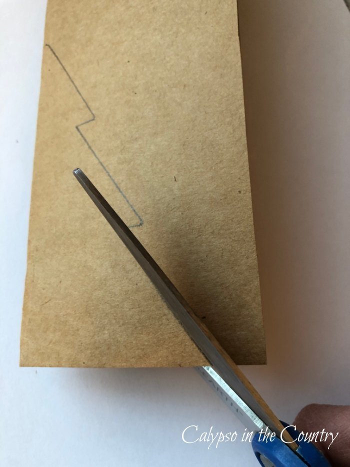 Cutting tree pattern on folded craft paper