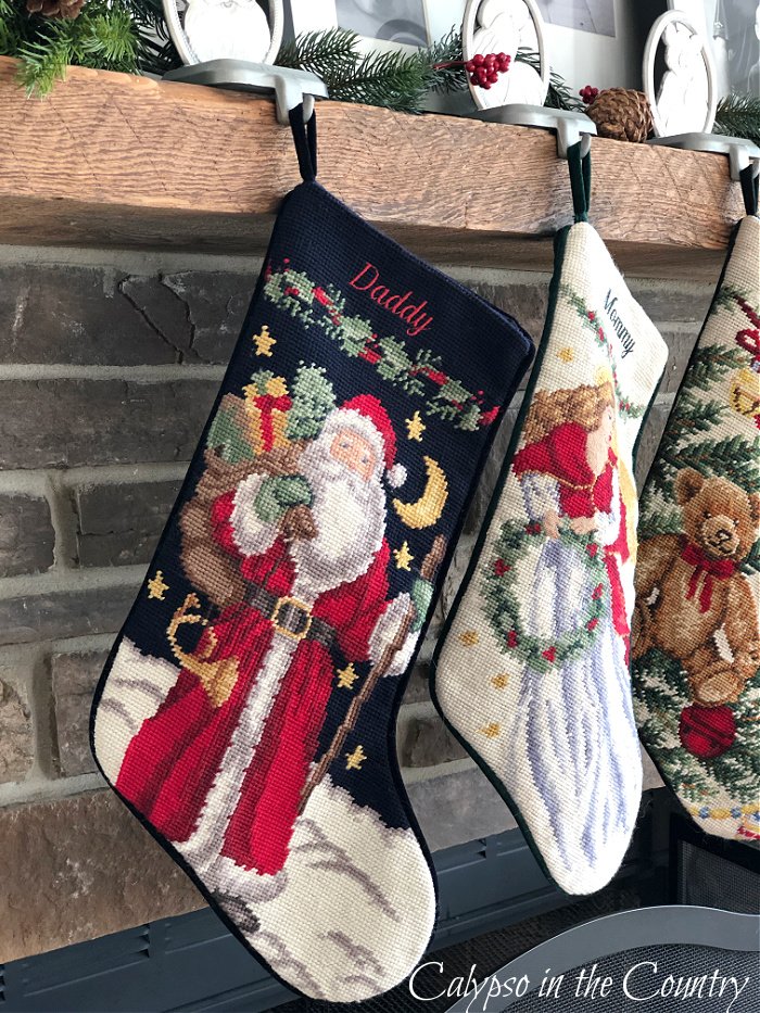 Needlepoint stockings hanging on rustic stone fireplace - Christmas stocking display ideas