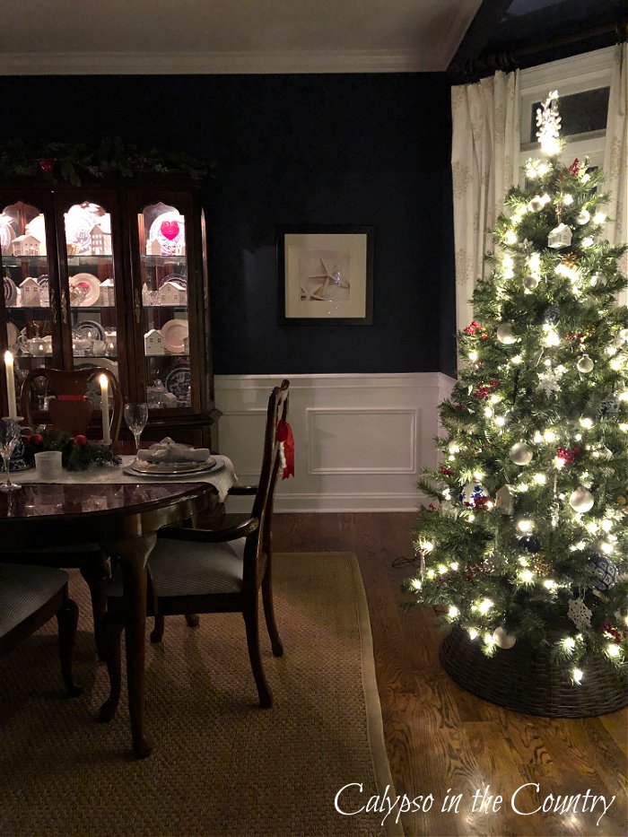 Navy blue dining room at night with lit Christmas tree