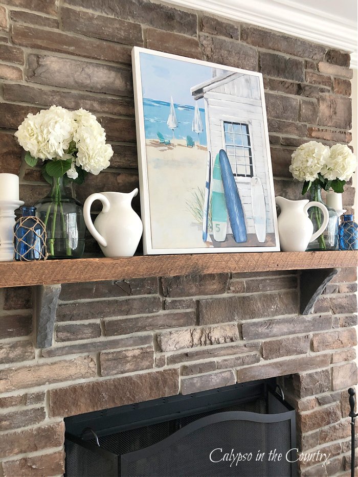 Stone fireplace with coastal art and accessories on wood mantel