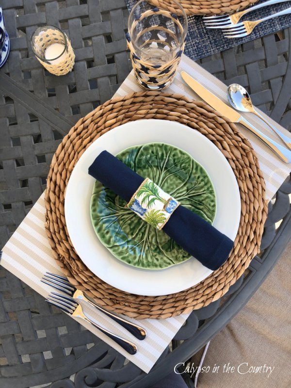 Patio table setting with seagrass plate charger and green cabbage plates.