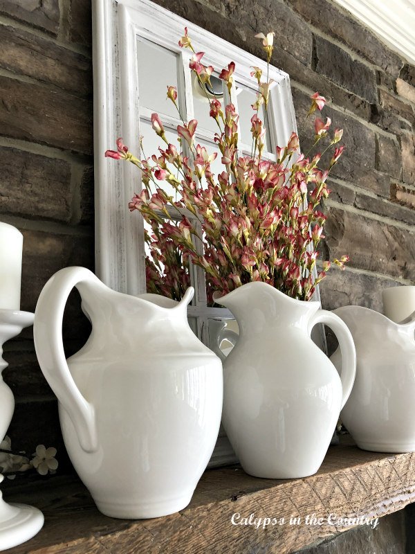 White pitchers and flowers on mantel - spring fireplace decor