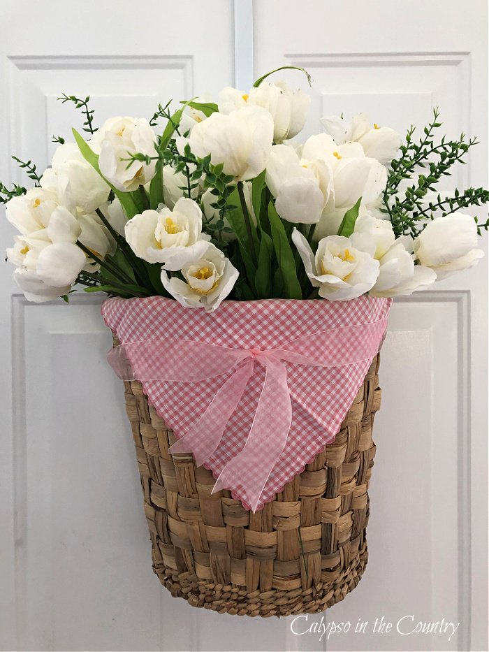 White tulips in seagrass door basket with pink gingham