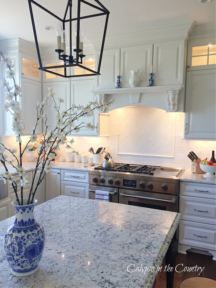 blue and white porcelain vase with flower stems in white kitchen island decorating ideas for spring