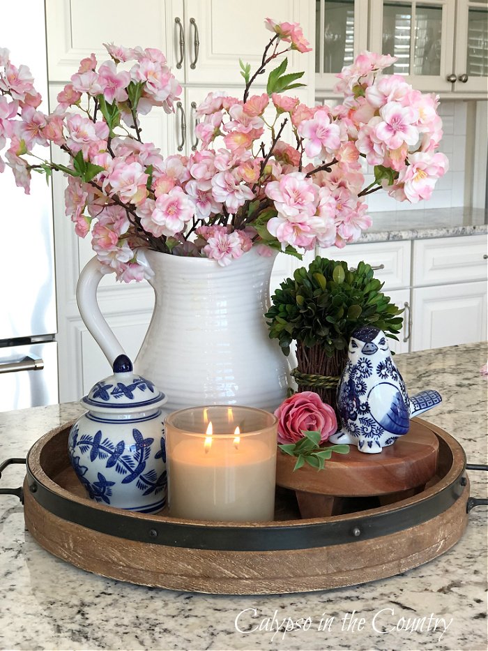 Pink cherry blossoms in white pitcher on wooden tray vignette - kitchen island decorating ideas for spring