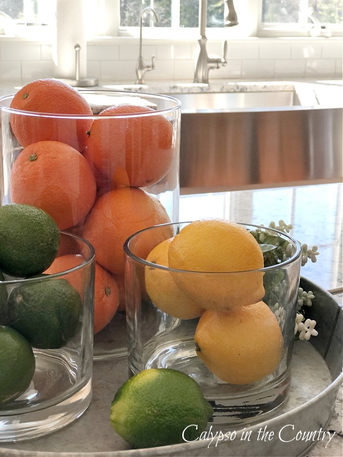 Oranges, lemons and limes in glass containers on tray - kitchen island decorating ideas