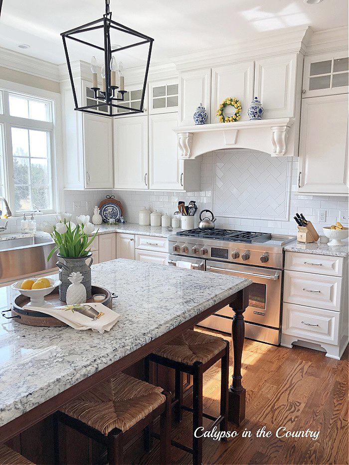 White kitchen with spring kitchen island centerpiece - flowers and lemons on tray