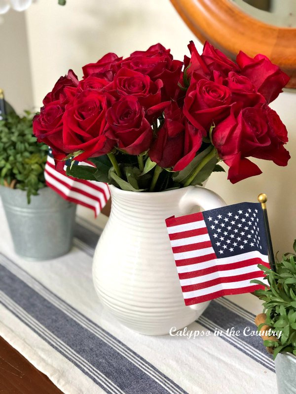 Red roses in white pitcher with flags - goodbye May hello June