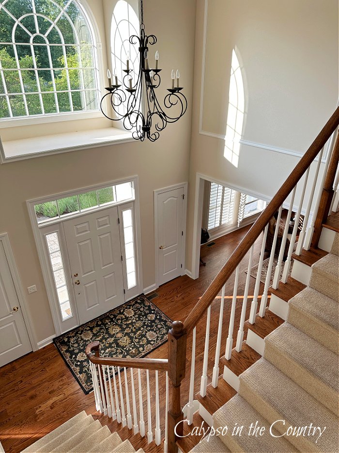 Stairs in two story foyer with arched window and sunlight - Summer Foyer Decorating Ideas