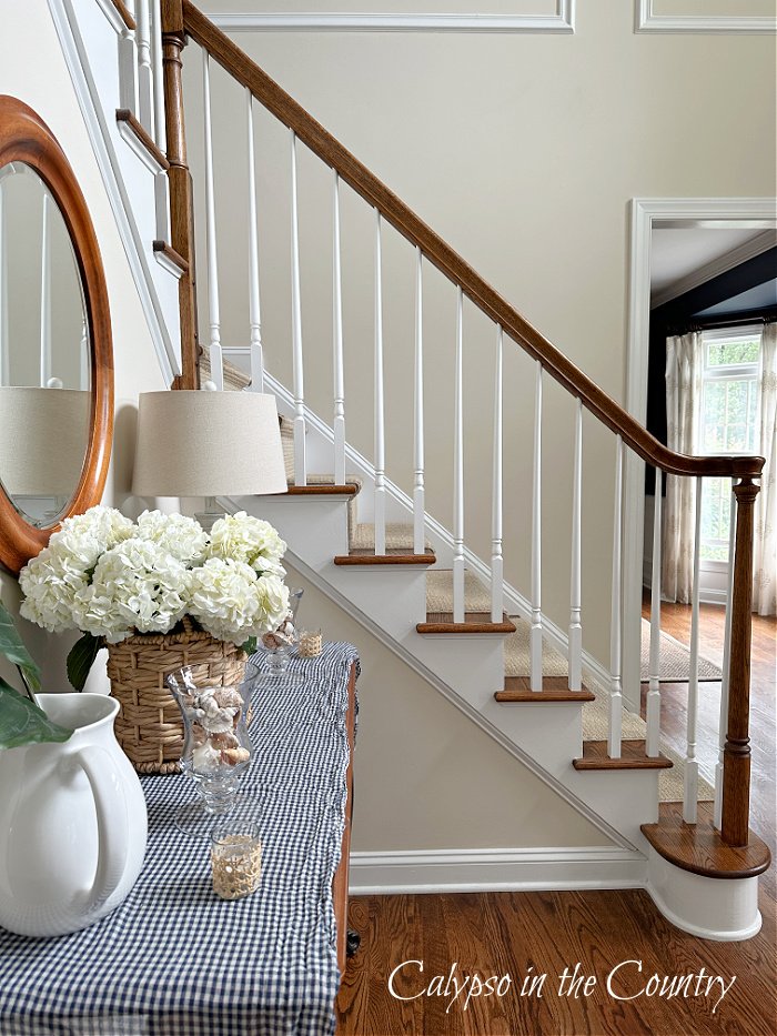 Traditional staircase with white spindles in summer entryway