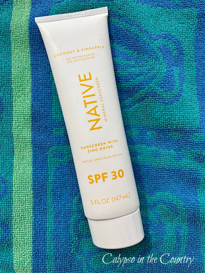Native sunscreen on blue and green beach towel - what to pack in your beach bag