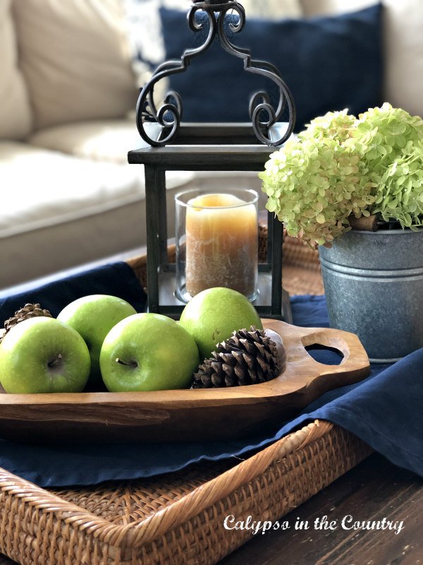 Green apples and hydrangeas on wicker tray of coffee table - end of summer decorating ideas