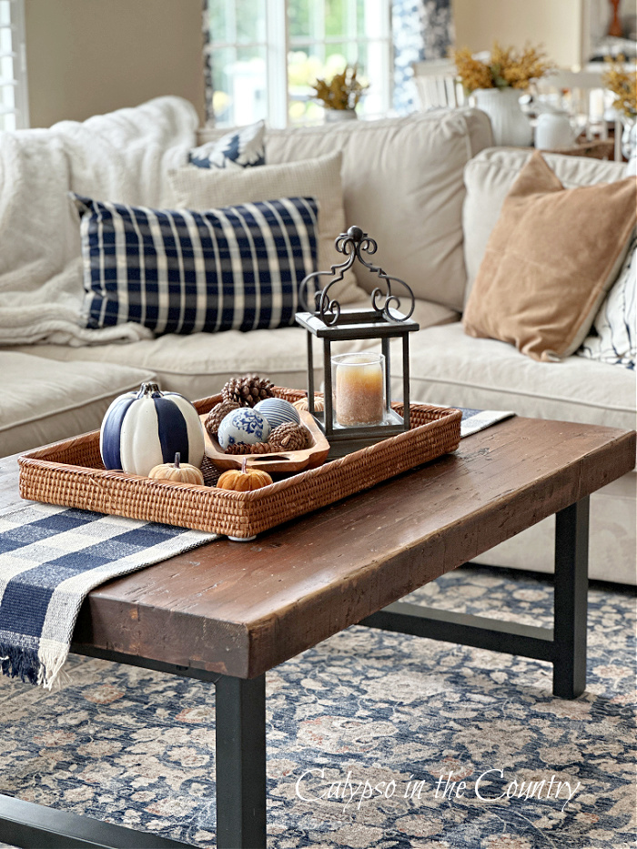 wood coffee table in front of sectional sofa with navy blue accessories - fall aesthetic ideas
