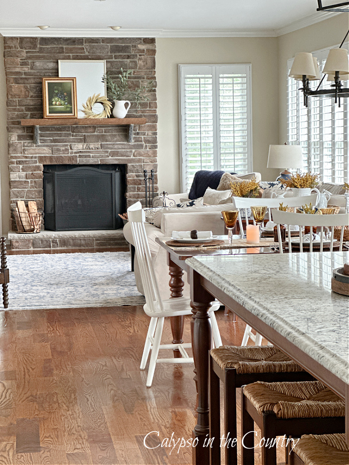 Open concept kitchen and family room with stone fireplace decorated for fall