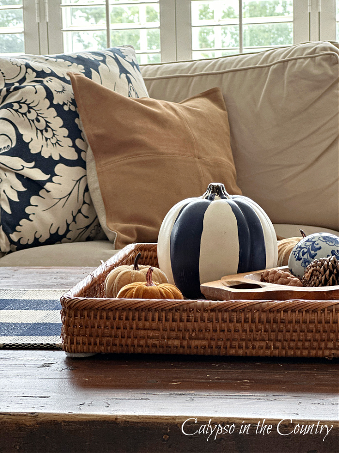 Navy blue and brown pillows and blue and white pumpkin on rattan tray - fall aesthetic