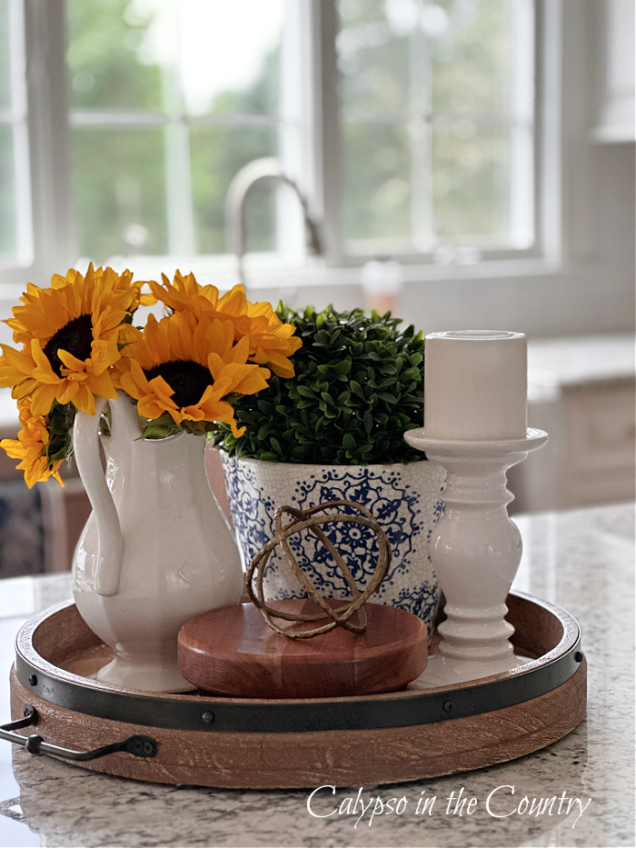 Sunflowers in white pitcher on round tray with candle and greenery - decorating with flowers ideas for fall