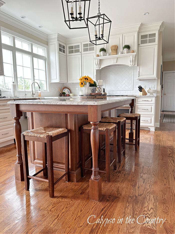 white kitchen with stained wood island and rush seat counter stools - fall aesthetic