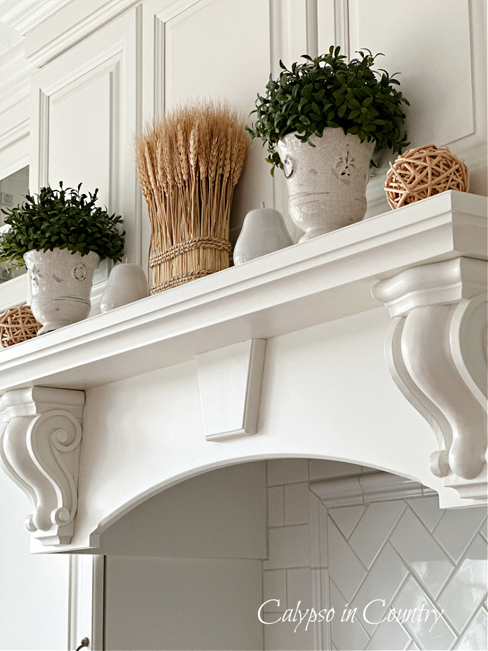 White stove mantel decorated with wheat and greenery for fall